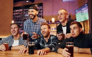 Fußballfans, die fernsehen. gruppe von menschen zusammen drinnen in der kneipe haben spaß am wochenende foto