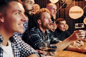 Fans jubeln und schreien. gruppe von menschen zusammen drinnen in der kneipe haben spaß am wochenende foto