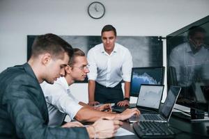 Vorstellung von Teamarbeit. Das Team von Börsenmaklern arbeitet in einem modernen Büro mit vielen Bildschirmen foto