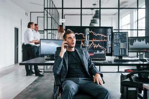 gewöhnlicher Bürotag. Team von Börsenmaklern arbeitet in Innenräumen mit vielen Bildschirmen foto