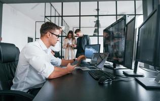 kerl mit brille konzentriert bei der arbeit. Das Team von Börsenmaklern befindet sich in einem modernen Büro mit vielen Bildschirmen foto