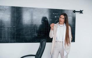 junge intelligente frau mit brille, die nahe tafel steht foto