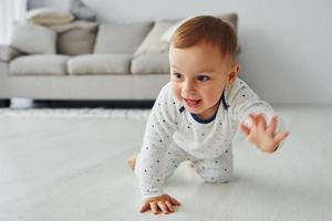 Fröhlicher kleiner Junge, viel Spaß. Interieur und Design eines schönen modernen Schlafzimmers tagsüber foto