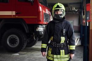 männlicher feuerwehrmann in schutzuniform, der in der nähe eines lkw steht foto