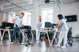 reinigt den Boden. gruppe von arbeitern reinigt tagsüber gemeinsam ein modernes büro foto