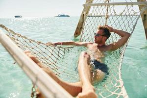 bei Sonnenbrillen. junger europäischer mann hat urlaub und genießt die freizeit am strand des meeres foto