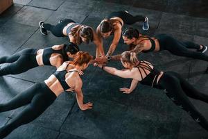 Plank-Übung. eine gruppe junger sportlicher leute hat drinnen im fitnessstudio einen crossfit-tag foto