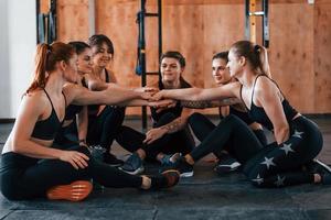 auf dem Boden sitzen. eine gruppe junger sportlicher leute hat drinnen im fitnessstudio einen crossfit-tag foto