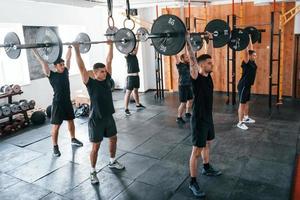 eine gruppe junger sportlicher leute hat drinnen im fitnessstudio einen crossfit-tag foto