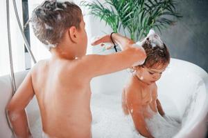 Zwei Kinder haben Spaß und waschen sich zu Hause in der Badewanne foto