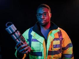 Polizist mit Bombe. futuristische neonbeleuchtung. junger Afroamerikaner im Studio foto