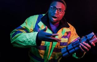 Polizist mit Bombe. futuristische neonbeleuchtung. junger Afroamerikaner im Studio foto
