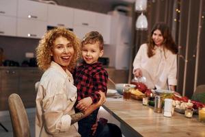 Wochenende zusammen verbringen. Die glückliche Familie von Mutter, Tochter und Sohn steht abends in der Küche foto