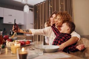 Die glückliche Familie von Mutter, Tochter und Sohn steht abends in der Küche foto