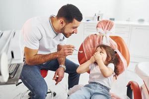 kleines mädchen, das männlichen zahnarzt in der klinik besucht. Konzeption der Stomatologie foto