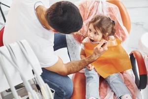 kleines mädchen, das männlichen zahnarzt in der klinik besucht. Konzeption der Stomatologie foto