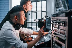 Vorstellung von Teamarbeit. Zwei Jungs sind drinnen im Radiostudio und sind mit Sendungen beschäftigt foto