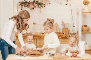 kaukasische mutter und töchter bereiten weihnachtsplätzchen in der küche zu. foto