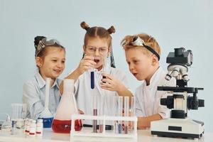 reagenzgläser mit bunter flüssigkeit. Kinder in weißen Mänteln spielen einen Wissenschaftler im Labor, indem sie Geräte verwenden foto