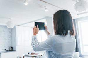 digitales Tablet in den Händen. junge frau ist tagsüber drinnen im smart house room foto