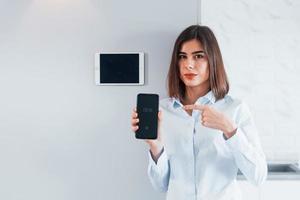 Steuern des Hauses durch eine Berührung. junge frau ist tagsüber drinnen im smart house room foto