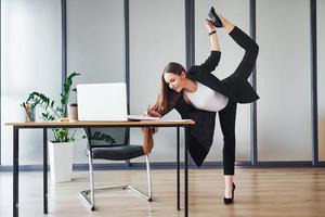 mit Laptop. junge erwachsene frau in formeller kleidung ist drinnen im büro foto