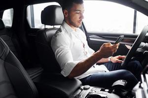 junger Mann in weißem Hemd sitzt in einem modernen neuen Automobil foto