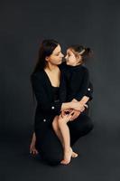 Mutter und Tochter sind zusammen im Studio vor schwarzem Hintergrund foto