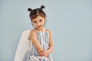 süßes kleines Mädchen sitzt nach der Impfinjektion drinnen im Krankenhaus foto