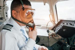 in Sauerstoffmaske. Pilot bei der Arbeit im Passagierflugzeug. Vorbereitung für den Start foto