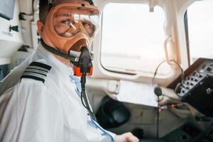 in Sauerstoffmaske. Pilot bei der Arbeit im Passagierflugzeug. Vorbereitung für den Start foto