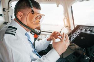 in Sauerstoffmaske. Pilot bei der Arbeit im Passagierflugzeug. Vorbereitung für den Start foto