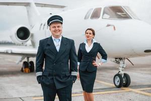 Mann mit Frau. Flugzeugbesatzung in Arbeitsuniform ist zusammen im Freien in der Nähe des Flugzeugs foto