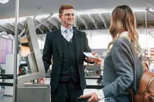 männlicher arbeiter, der frau hilft. junge weibliche touristin ist tagsüber am flughafen foto