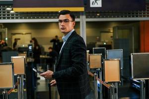 moderner Hintergrund. Der junge Geschäftsmann in formeller Kleidung ist tagsüber am Flughafen foto