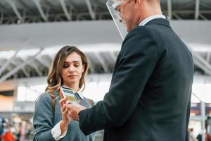 Impfpass am Telefon. junge weibliche touristin ist tagsüber am flughafen foto