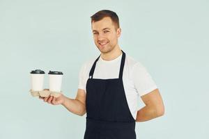 Mann in Uniform steht mit Getränken in der Hand im Studio foto