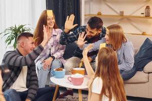 mit Aufklebern auf der Stirn. gruppe von freunden feiern zusammen drinnen foto