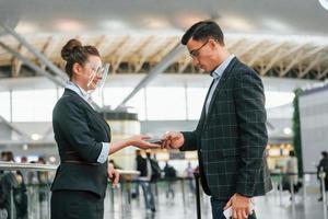 Arbeiten mit Dokumenten. Der junge Geschäftsmann in formeller Kleidung ist tagsüber am Flughafen foto