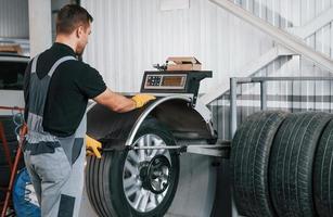 Befestigung des Reifens. Mann in Uniform arbeitet im Autoservice foto