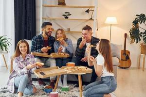 mit leckerer Pizza. gruppe von freunden feiern zusammen drinnen foto