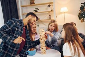 Holzturmspiel auf dem Tisch. gruppe von freunden feiern zusammen drinnen foto