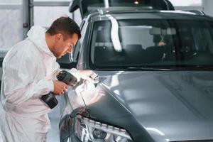 mit speziellen Geräten. Mann in Uniform arbeitet im Autoservice foto