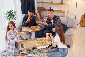 leckere Pizza essen. gruppe von freunden feiern zusammen drinnen foto