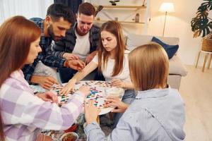 auf Puzzlespiel konzentriert. gruppe von freunden feiern zusammen drinnen foto