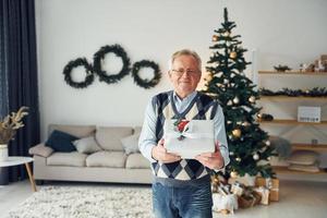 feiert neujahr und steht in der nähe des weihnachtsbaums. senior mann in schöner kleidung ist zu hause foto