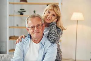 lächelnd und umarmend. Senior Mann und Frau sind zusammen zu Hause foto