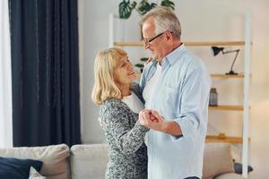 Tanzen im Wohnzimmer. Senior Mann und Frau sind zusammen zu Hause foto