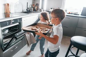 Essen backen. kleiner Junge und Mädchen, die Weihnachtsplätzchen in der Küche zubereiten foto