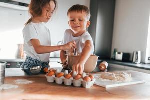 mit Teig arbeiten. kleiner Junge und Mädchen, die Weihnachtsplätzchen in der Küche zubereiten foto